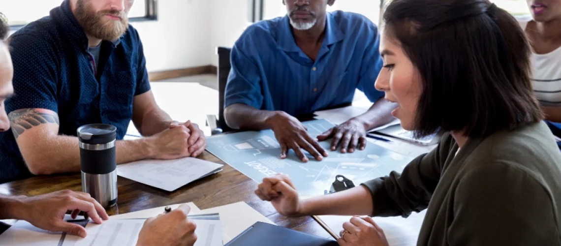 A group of people sitting at a table in a conference room having a meeting.